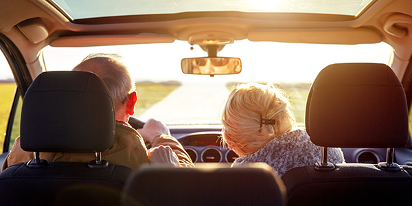 Old couple in the front of a car seen from the back seat